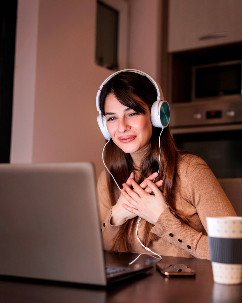 Een vrouw die een zoom gesprek via haar laptop heeft en glimlacht wat slaat op het effect van een coaching sessie bij Maura ten Hoopen van Restful Mind Coaching